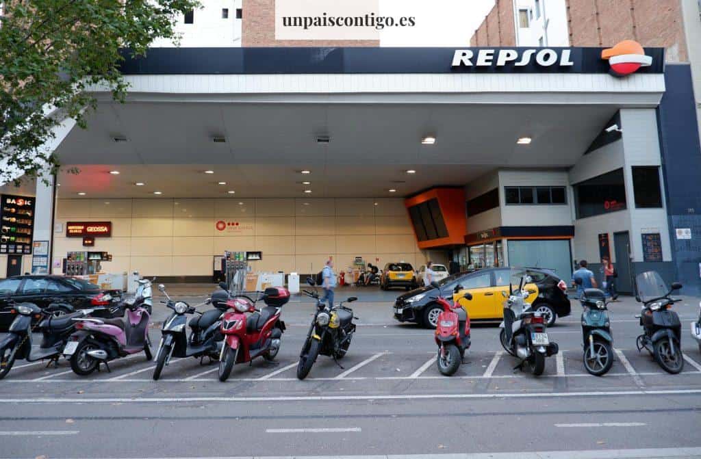 Row of Motor Scooters Parked in Front of a Filling Station