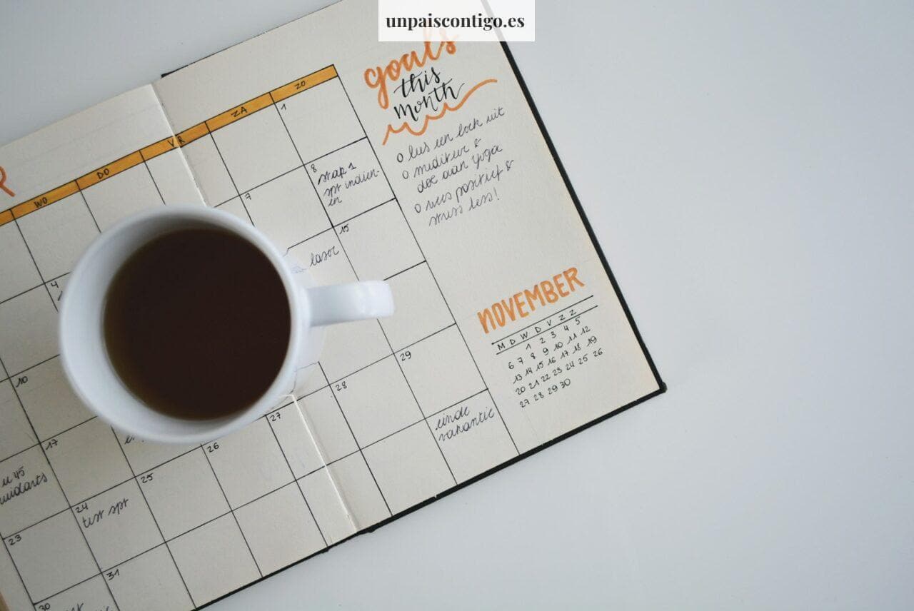 white ceramic mug with coffee on top of a planner