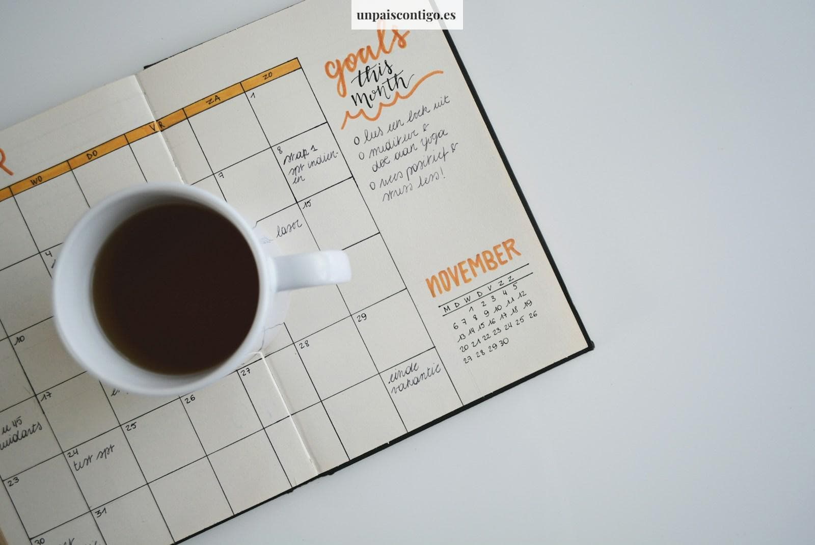 white ceramic mug with coffee on top of a planner