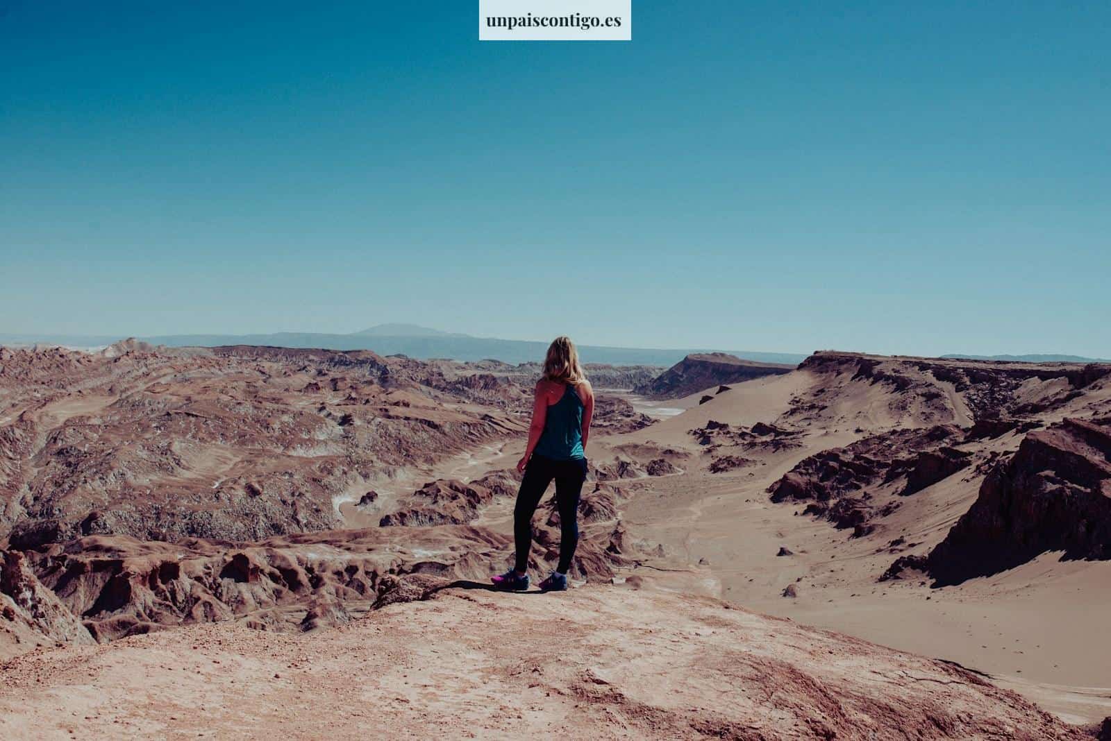 woman on black dress atop of canyon looking at the mountainous terrain during daytime